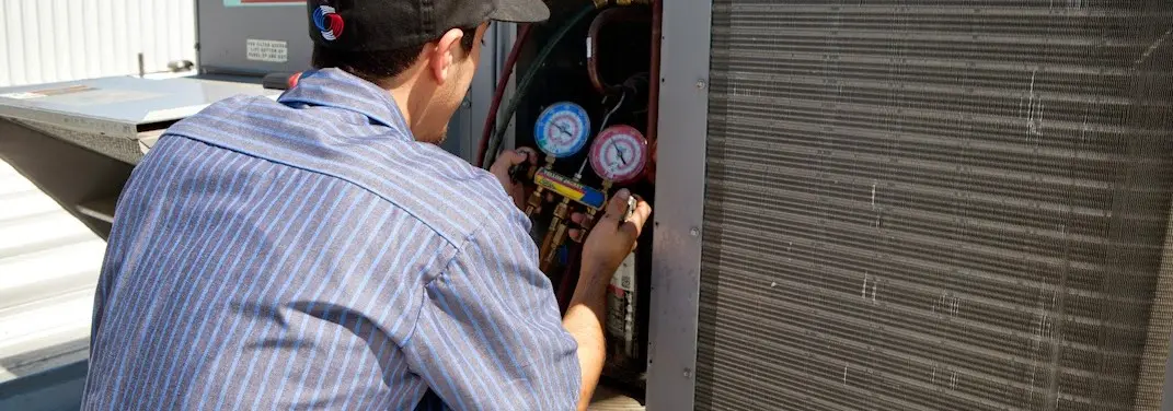 HVAC technician servicing a condenser unit in Newberg
