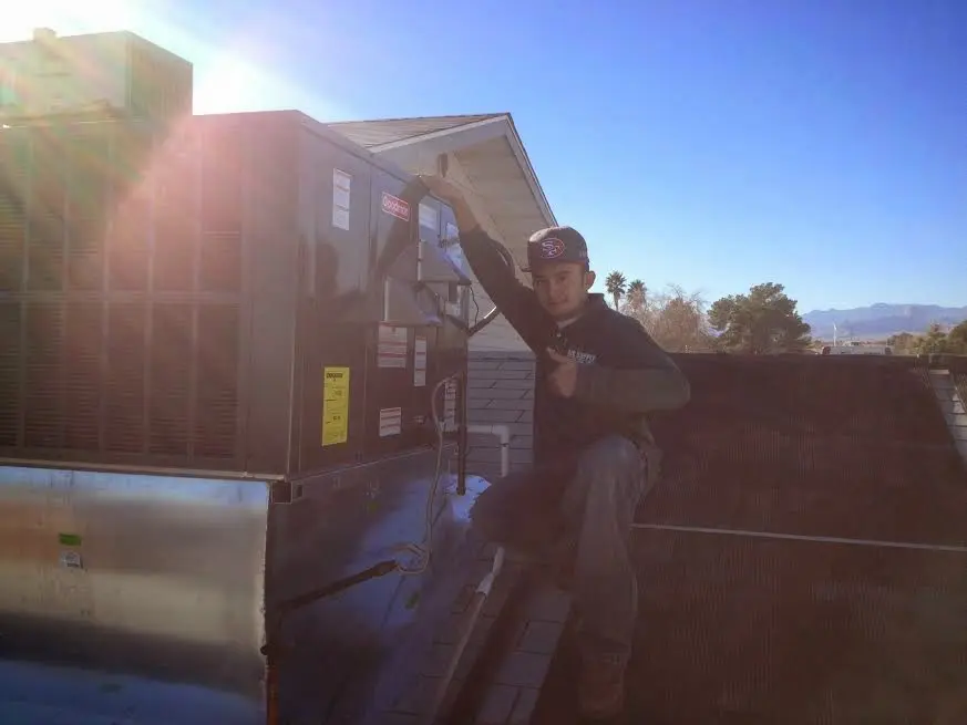 HVAC technician performing Heat Pump Repair on a rooftop unit in Newberg